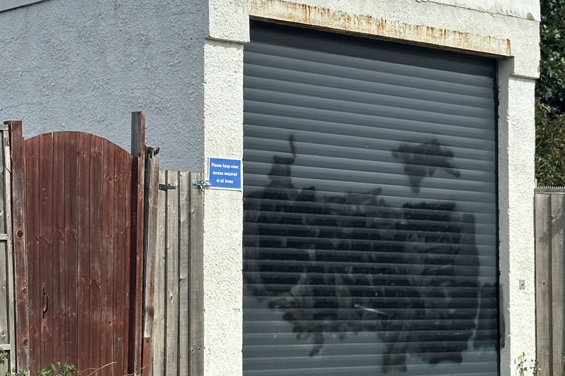 corner garage with grey roller door and rust staining g